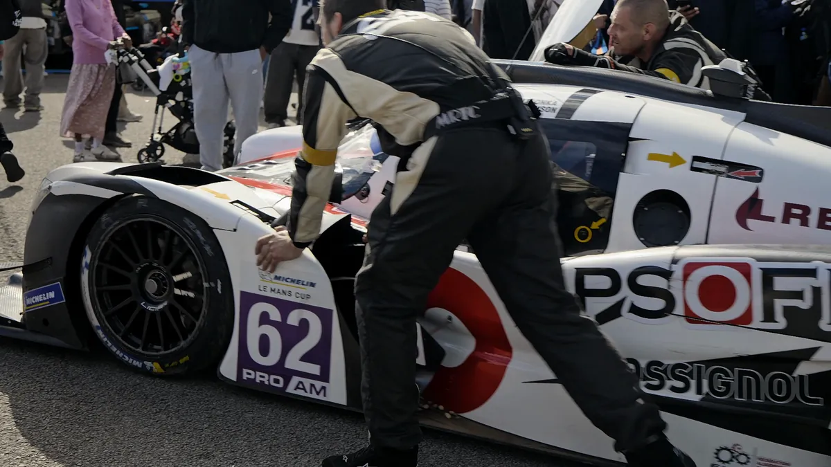 A mechanic leaning into a white prototype in the pit lane
