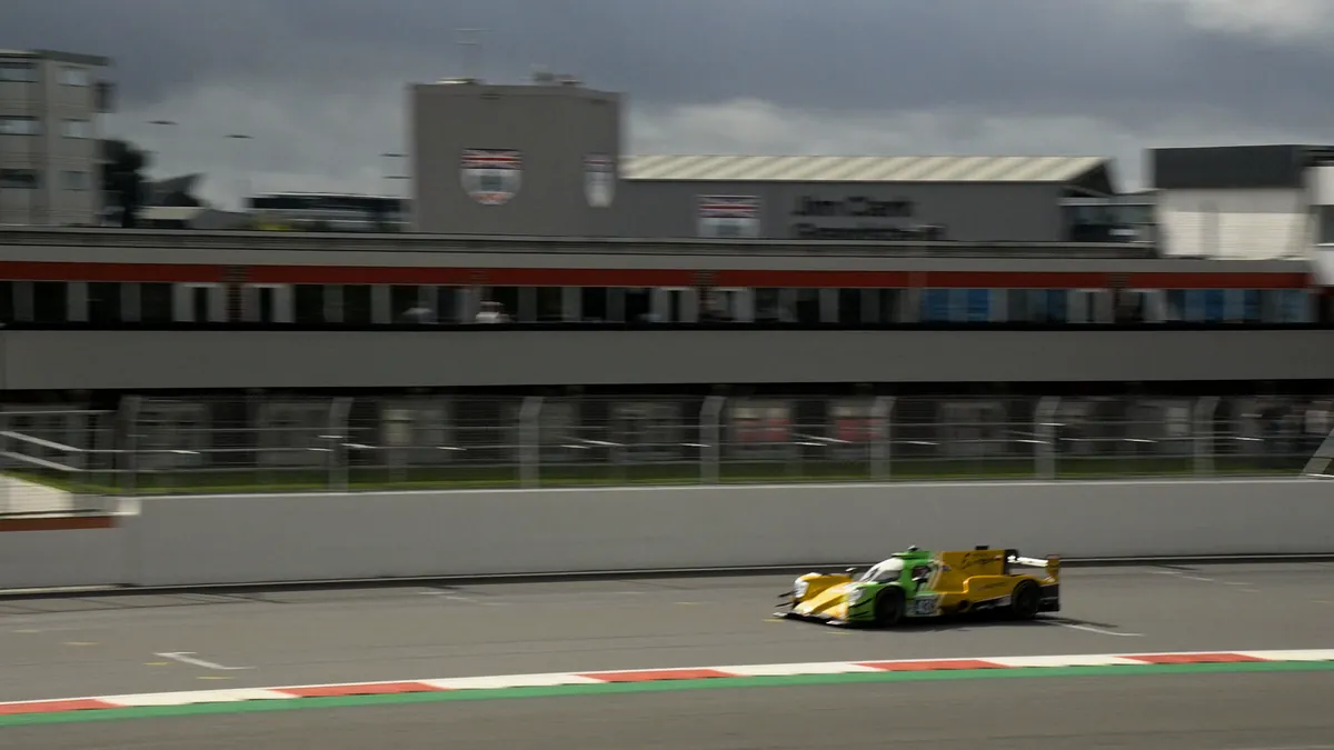 A prototype streaking past the pit buildings on a panning shot