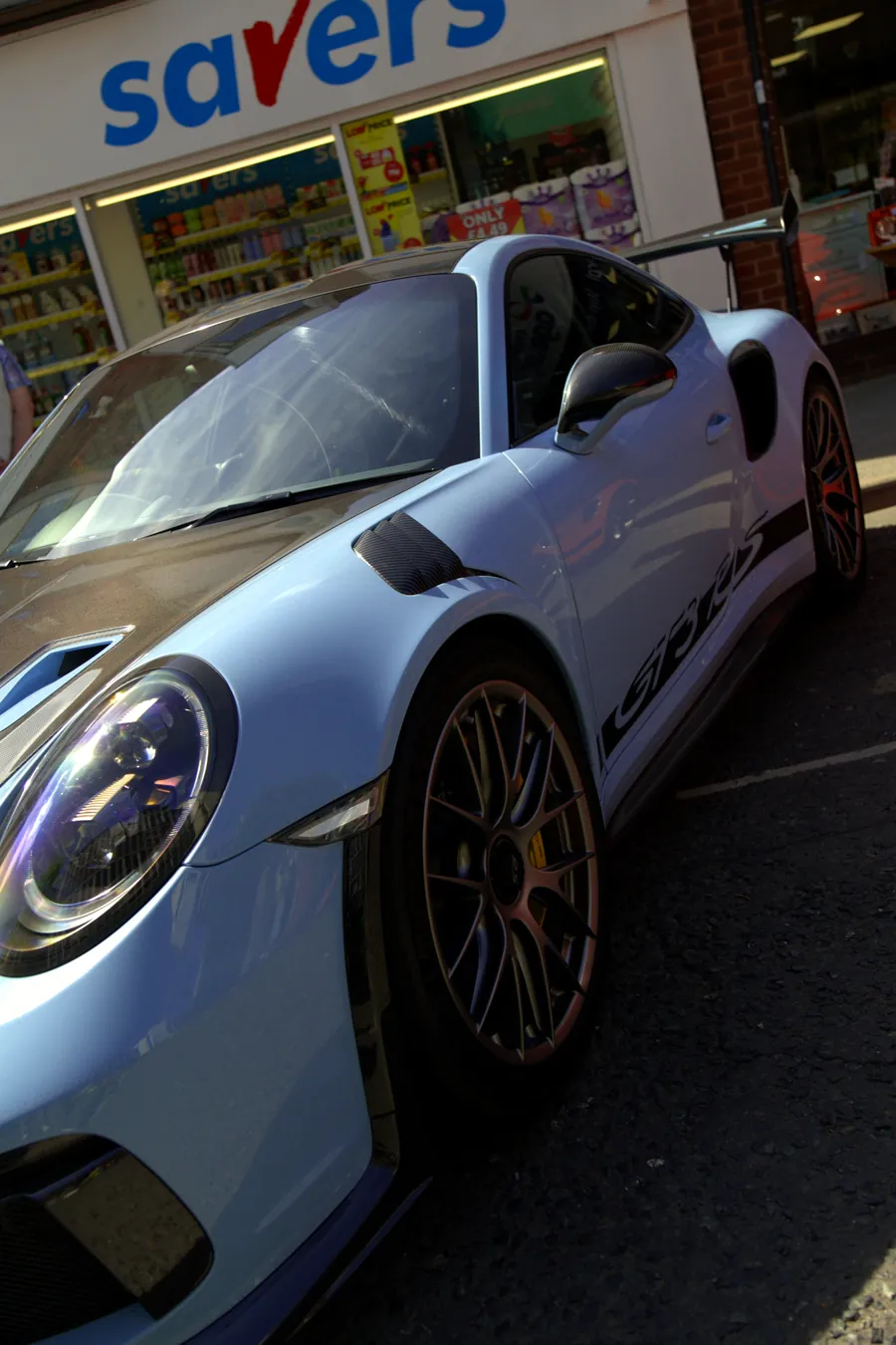 A pale blue Porsche parked on the high street