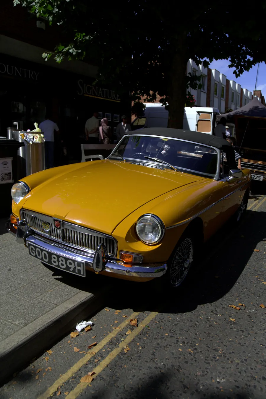 A yellow classic MG parked at the kerb