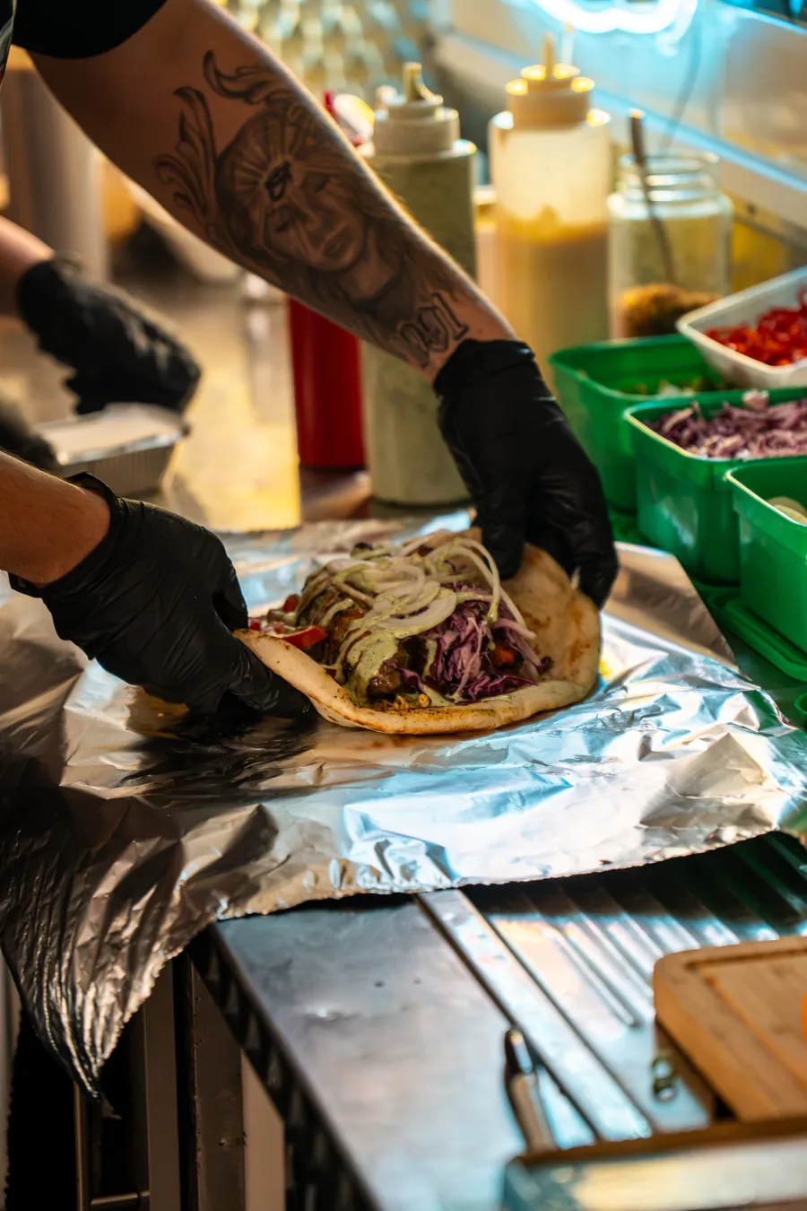 Gloved hands folding a kebab wrap